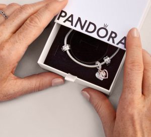 Two hands holding a Pandora bracelet