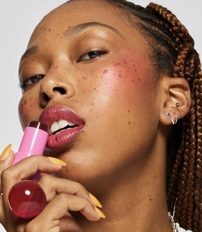 A woman putting Milk's new jelly blusher on her lips.